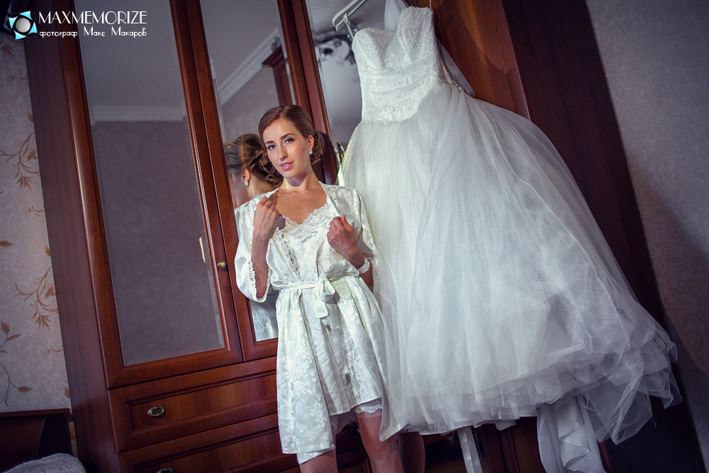 Невеста со свадебным платьем у зеркала